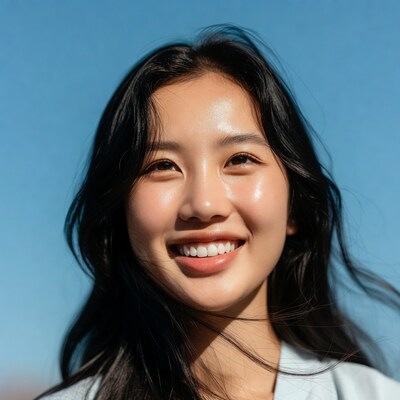 Asian woman smiling against blue sky