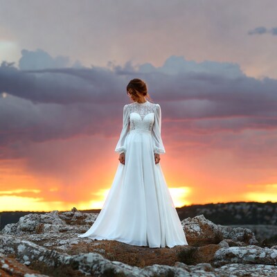 Bride in white gown on sunset cliff