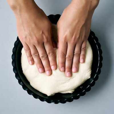 Hands pressing dough into tart pan