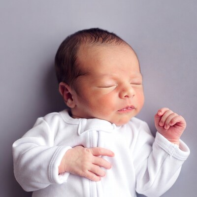 Newborn baby sleeping in white onesie