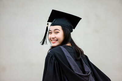 Asian woman in graduation gown smiling