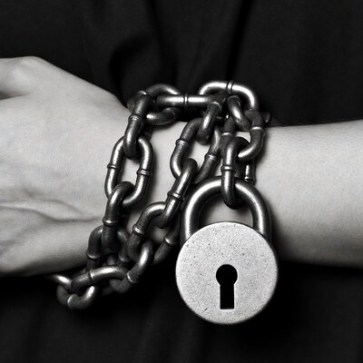 Woman's hand bound by chain and lock