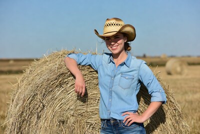 Cowgirl leaning on hay bale