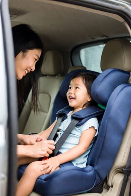 Asian mom buckling baby girl in car seat