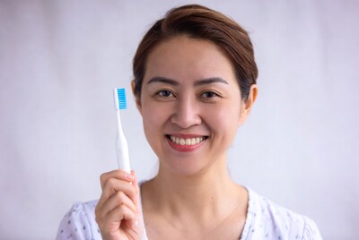 Asian woman holding blue toothbrush
