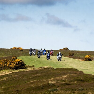 Motorcyclists riding on grassy hill