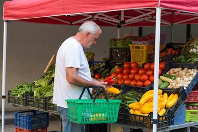 Elderly man shopping vegetables at market stall