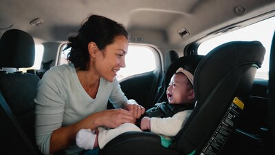 Mother buckling baby in car seat