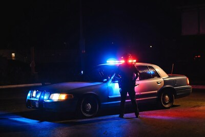 Policeman standing by patrol car at night
