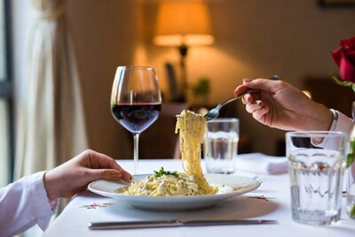 Hands twirling fettuccine alfredo with wine