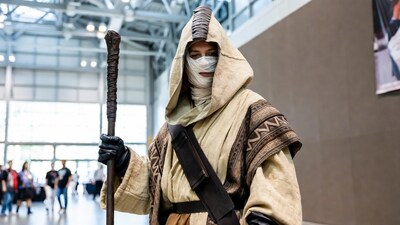 Woman in hooded Jedi cosplay with staff