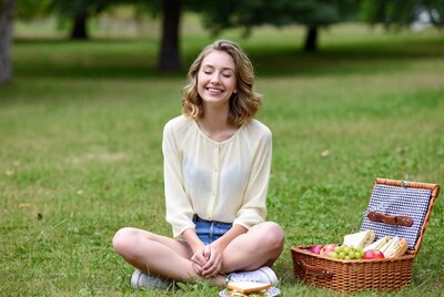 Smiling woman with picnic basket in grass