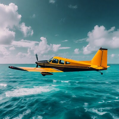 Yellow Cessna flying over turquoise ocean
