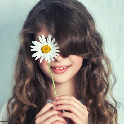 Girl peeking through daisy flower