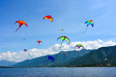 Colorful kites flying over lake and mountains
