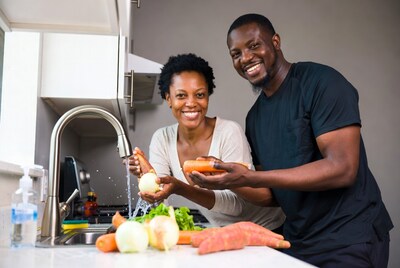 African couple washing vegetables in kitchen