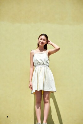 Asian woman in white dress against yellow wall