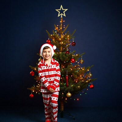 Boy in Santa pajamas by Christmas tree