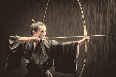 Woman shooting Japanese bow in rain