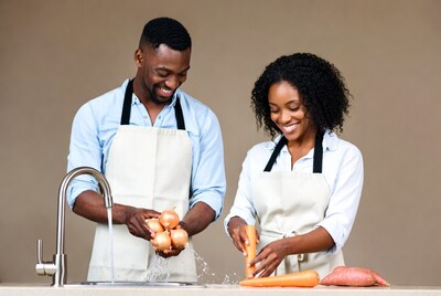 African couple washing vegetables in kitchen