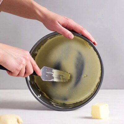 Woman greasing cake pan with butter