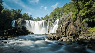 Woman standing before majestic waterfall