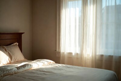 Sunlit Bed with White Sheer Curtains