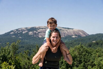 Mother carrying son on shoulders with mountain