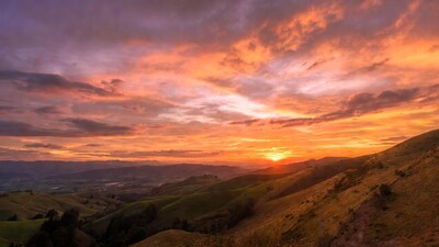 Vibrant Sunset Over Rolling Green Hills