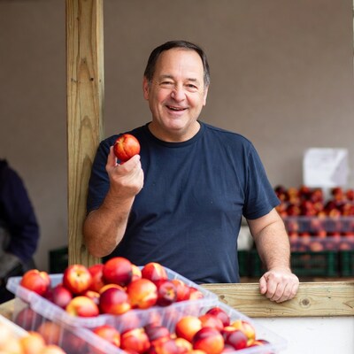 Smiling man holding peach at market stand