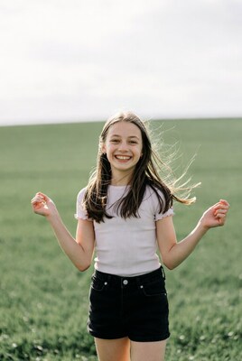 Smiling girl in field with arms raised