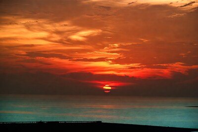 Sunset over sea with pier silhouette