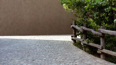 Wooden fence with greenery on cobblestone path
