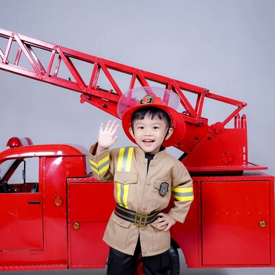 Asian boy waving in firefighter costume