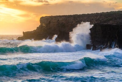 Waves crashing against sunset sea cliffs