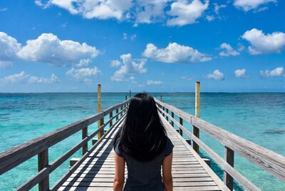 Woman walking on pier over turquoise ocean