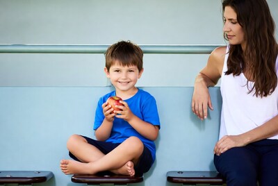 Boy holding red apple with mom