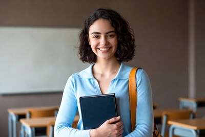 Smiling woman holding book in classroom