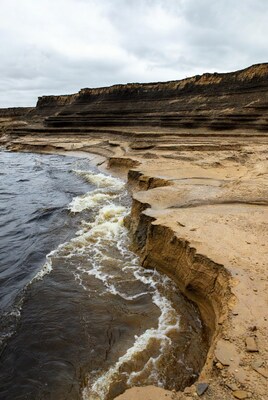 Layered Sandstone Cliffs by River