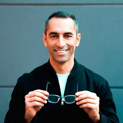 Man holding glasses against gray wall