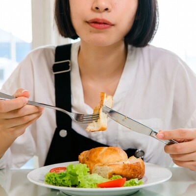 Asian woman cutting bread with fork