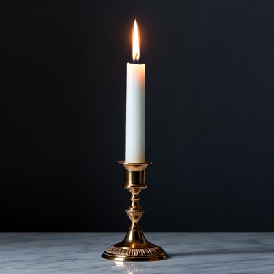 Burning white candle in gold candlestick