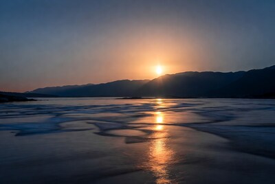 Sunrise over icy lake and mountains