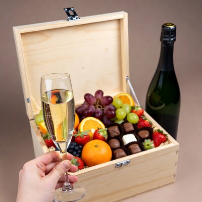 Hand Holding Champagne Glass by Fruit Chocolate Box