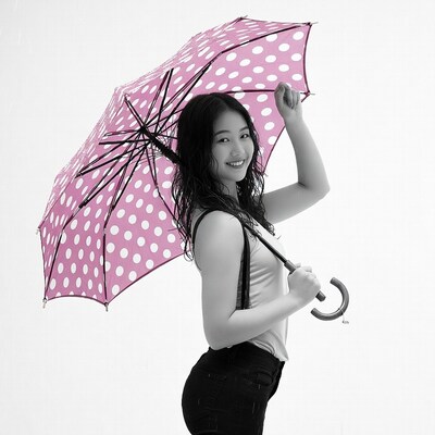 Asian woman holding pink polka dot umbrella