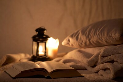 Open book by lantern on bed