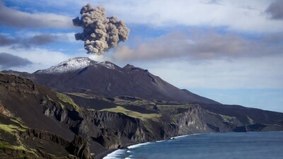 Erupting volcano over ocean cliffs