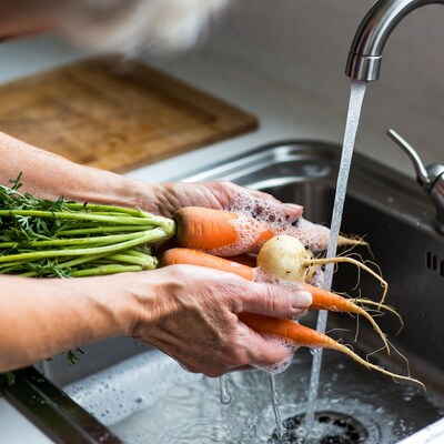 Woman washing carrots in sink