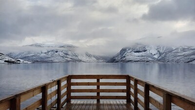 Wooden pier over misty lake with snowy mountains