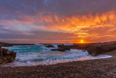 Sunset over rocky beach with waves